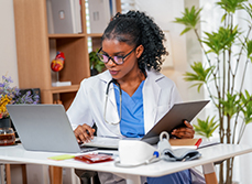 Une femme médecin consulte son ordinateur dans son cabinet - MACSF