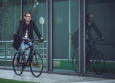 Un homme sur un vélo passe devant des baies vitrées - MACSF