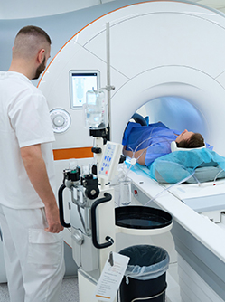 Un patient est allongé dans un scanner pendant qu’un technicien médical surveille l’examen - MACSF