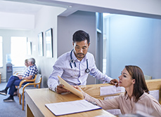 Un médecin discute d'un dossier avec sa secrétaire à l'accueil - MACSF