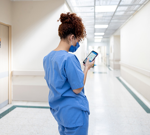 Une infirmière consultant son téléphone portable dans le couloir de l'hôpital - MACSF
