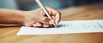 Main d'une personne écrivant sur un document - MACSF
