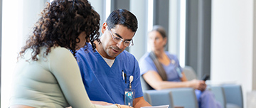 Un infirmier parle avec une patiente dans la salle d'attente de l'hôpital - MACSF