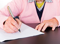 Une femme âgée signe un document - MACSF
