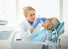 Une femme dentiste réalise des soins sur une patiente - MACSF