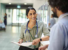 Une femme médecin discute avec un collègue dans un couloir d'hôpital - MACSF