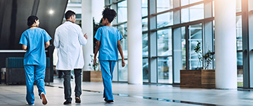 Trois professionnels de santé marchent dans le hall d'un hôpital - MACSF