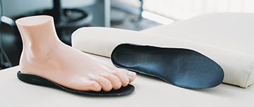 Un pied mannequin posé sur une semelle orthopédique noire - MACSF