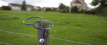 Un stéthoscope posé sur le poteau d'un pré avec la campagne en arrière-plan - MACSF