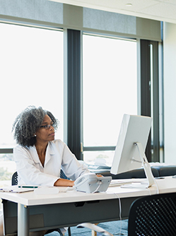 Une femme médecin est installée devant son ordinateur - MACSF
