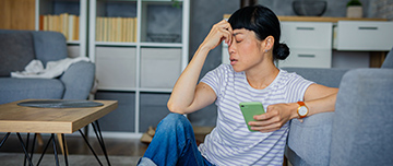 Une femme désabusée avec un smartphone dans la main - MACSF