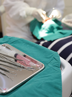 Chirurgien-dentiste pratiquant des soins et plateau d'instruments dentaires - MACSF