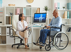 Une femme médecin en consultation avec une homme en fauteuil roulant - MACSF