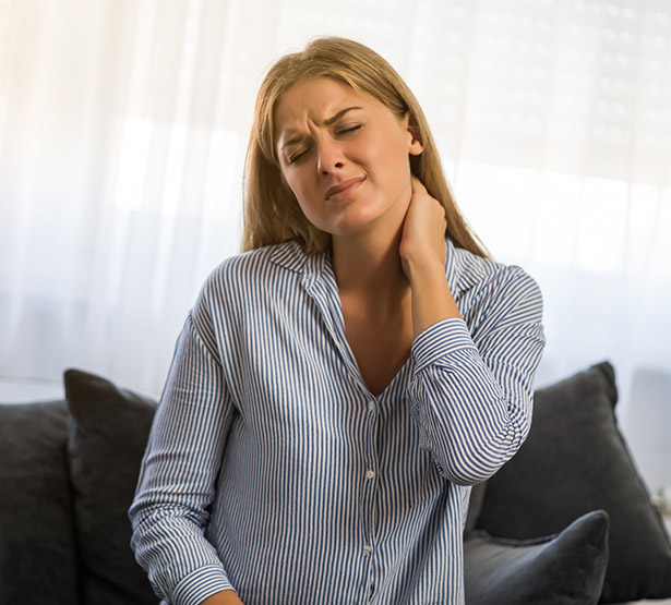 Une femme assise se tient le coup avec une expression de douleur - MACSF