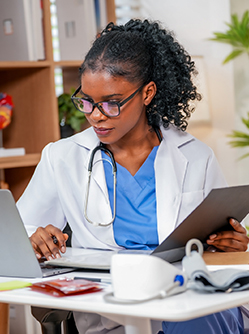 Une femme médecin consulte son ordinateur dans son cabinet - MACSF