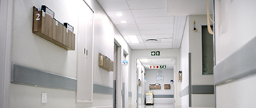 Des dossiers patients dans des bannettes accrochées au mur d'un couloir d'hôpital - MACSF