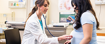 Une sage-femme pose le stéthoscope sur le ventre de la femme enceinte - MACSF
