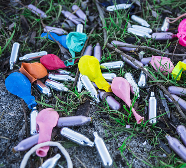 Des cartouches de gaz hilarant et des ballons dégonflés étalés dans l'herbe - MACSF