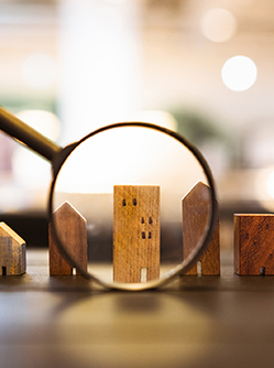 Représentation de 5 petites maisons en bois alignées et pointées par une loupe - MACSF