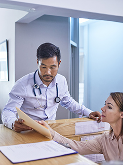 Un médecin discute d'un dossier avec sa secrétaire à l'accueil - MACSF