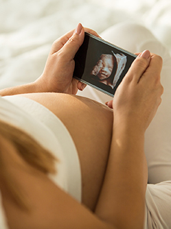 Une femme enceinte regarde l'échographie sur son téléphone 3D- MACSF