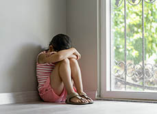 Une jeune fille maltraitée assise près d'une fenêtre | MACSF