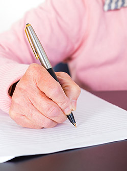 Une femme âgée signe un document - MACSF