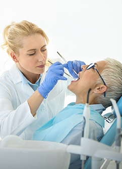Une femme dentiste réalise des soins sur une patiente - MACSF