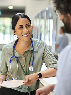 Une femme médecin discute avec un collègue dans un couloir d'hôpital - MACSF