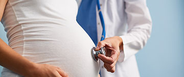 Une sage-femme applique le stéthoscope sur la ventre d'une femme enceinte - MACSF