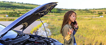 Une femme au téléphone adossée à sa voiture capot ouvert - MACSF