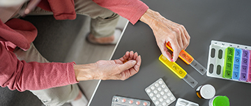 Gros plans sur les mains d'une femme âgée préparant son pilulier - MACSF