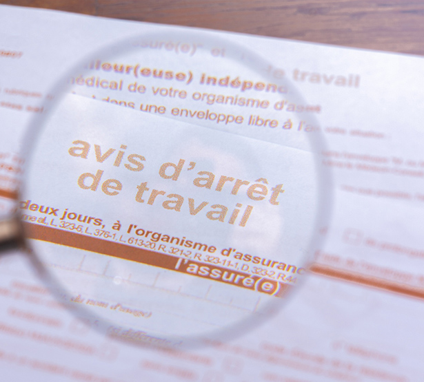 Gros plan à travers une loupe d’un formulaire officiel d’arrêt maladie de la sécurité sociale - MACSF