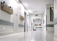 Des dossiers patients dans des bannettes accrochées au mur d'un couloir d'hôpital - MACSF