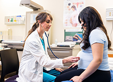 Une sage-femme pose le stéthoscope sur le ventre de la femme enceinte - MACSF