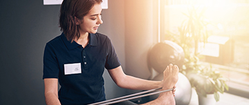 Une kinésithérapeute pratique des exercices de rééducation sur la jambe d'un patient - MACSF