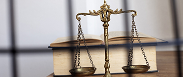 Un code pénal et la balance de la justice posés sur un bureau - MACSF