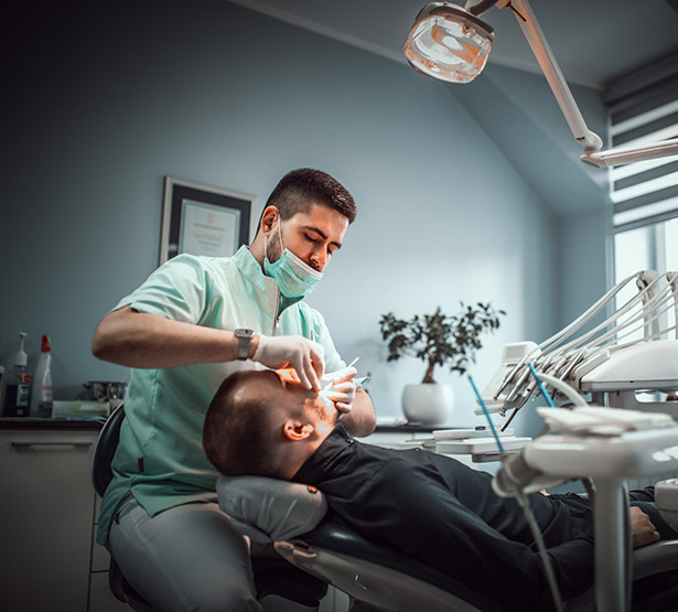 Un chirurgien-dentiste pratique des soins dentaires sur son patient - MACSF