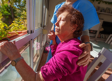 Une femme âgée assise près de la fenêtre avec la soignante - MACSF