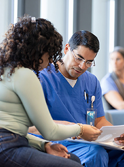 Un infirmier parle avec une patiente dans la salle d'attente de l'hôpital - MACSF