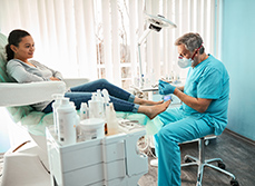 Un pédicure-podologue réalise des soins sur une patiente - MACSF