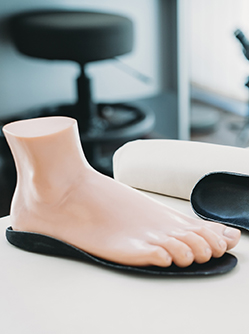 Un pied mannequin posé sur une semelle orthopédique noire - MACSF