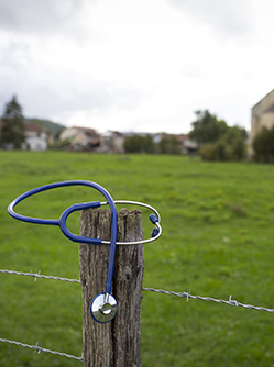 Un stéthoscope posé sur le poteau d'un pré avec la campagne en arrière-plan - MACSF