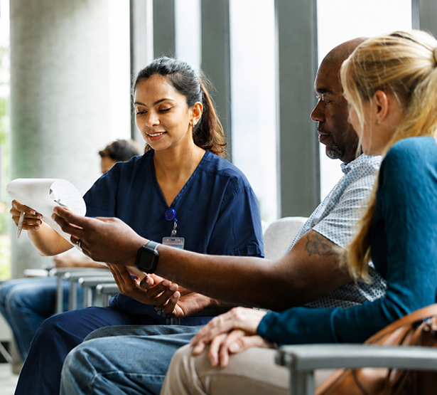 Une infirmière aide un patient à remplir un questionnaire en salle d'attente - MACSF
