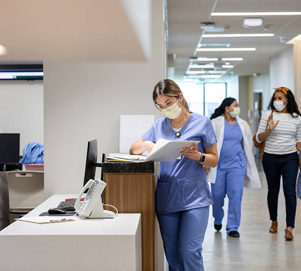 Une professionnelle de santé consulte un dossier sur le comptoir du service d'accueil de l'hopital - MACSF