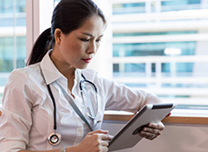 Une femme médecin regarde sa tablette - MACSF