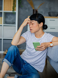 Une femme désabusée avec un smartphone dans la main - MACSF