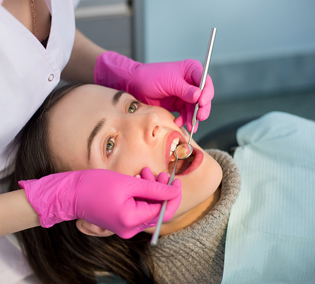 Une femme chirurgien-dentiste examine les dents d'une patiente avec des outils dentaires - MACSF