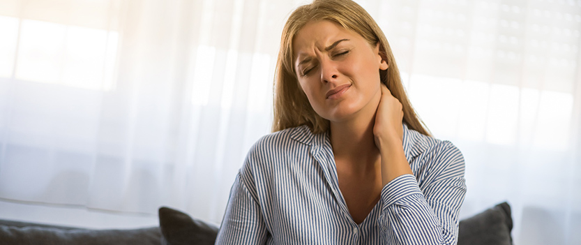 Une femme assise se tient le coup avec une expression de douleur - MACSF
