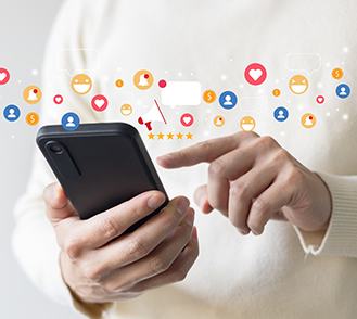 gros plan sur une main pianotant sur un smartphone, entourés d'un nuage de smileys - MACSF